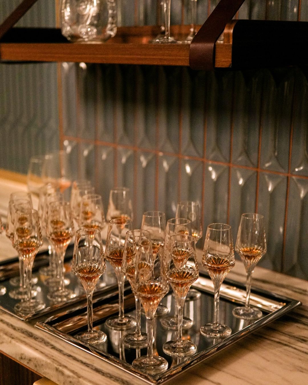 Crystal glasses of cognac lined up on a mirrored tray