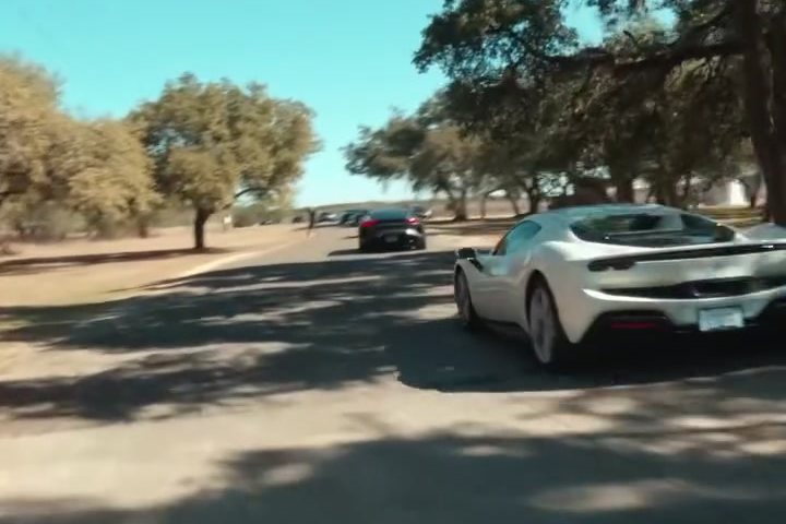 A white Ferrari driving under live oaks on a Texas back road
